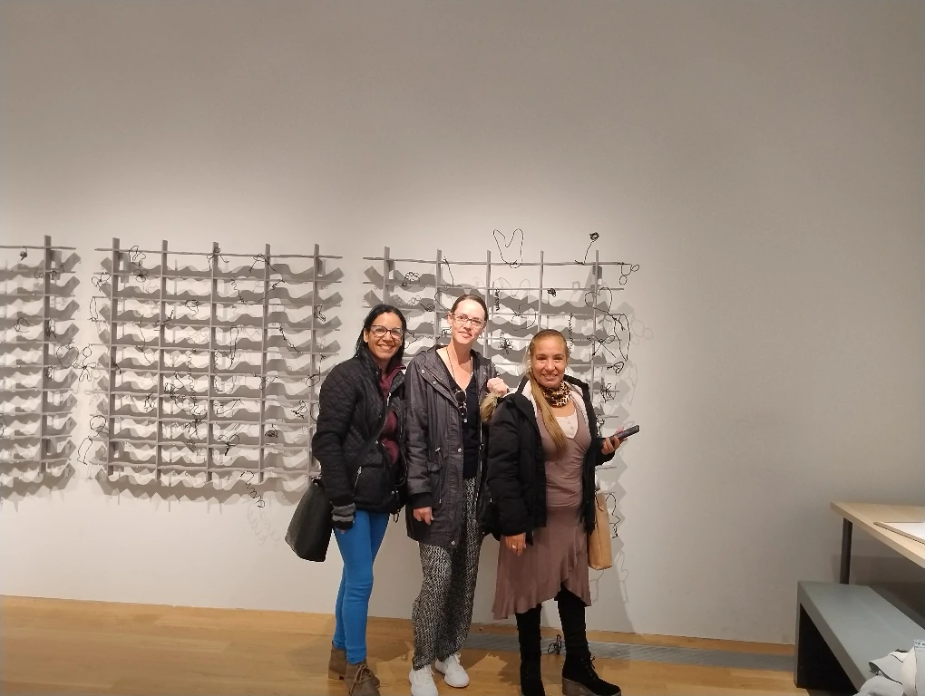 hree women pose in front of a wall adorned with a multitude of wires